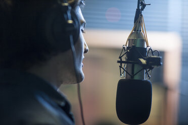 Male musician in recording studio, singing into microphone - ISF06758