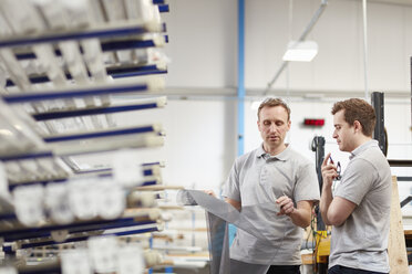 Manager prüft Stoff mit Arbeiter in einer Rollladenfabrik - CUF18029