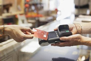 Cropped view of womens hand using credit card to make contactless payment on chip and pin machine - CUF18070