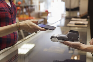 Cropped view of womans hands using smartphone to make contactless payment on smartphone - CUF18071