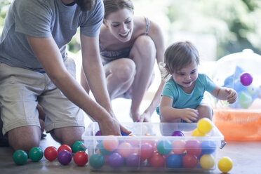 Eltern und Tochter spielen mit Bällen auf dem Boden - ISF06803