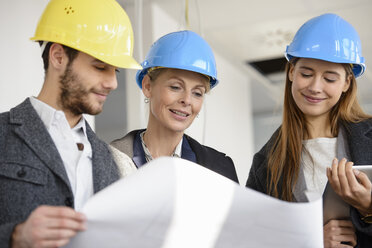 Architect looking at blue print with businesswomen in new office building - CUF18102