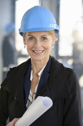 Porträt einer Geschäftsfrau mit blauem Schutzhelm in einem neuen Büro - CUF18105