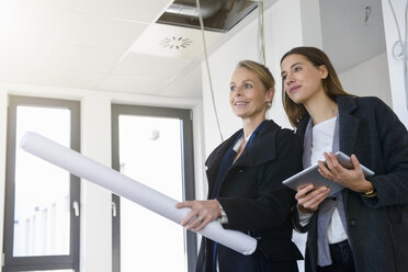 Businesswomen with blueprint inspecting in new office - CUF18108