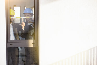 Young businesswoman and architect measuring window in new office - CUF18113