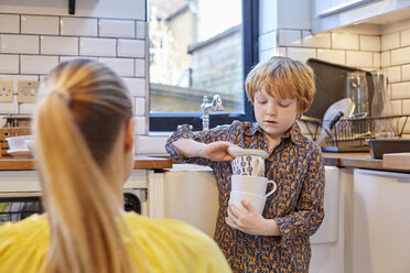 Junge trägt Stapel von Tassen in der Küche - CUF18212