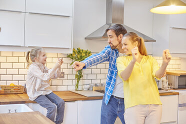 Daughter taking photograph of funny parents in kitchen - CUF18218