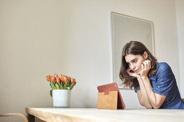 Junge Frau liest am Esstisch auf einem digitalen Tablet - CUF18225