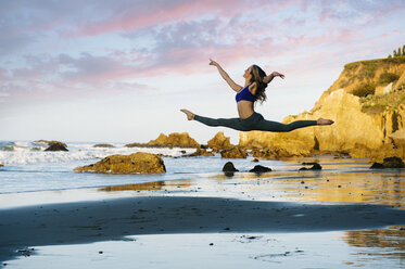 Young female ballet dancer jumping mid air on beach, Los Angeles, California, USA - ISF06855