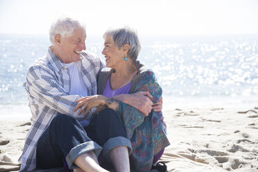 Senior couple sitting on beach, hugging, face to face, smiling - ISF06910