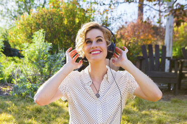 Mid adult woman wearing headphones, outdoors, smiling - ISF06926