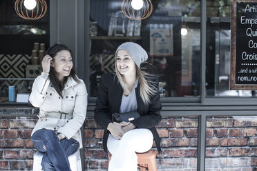 Zwei Freundinnen sitzen vor einem Stadtcafé - ISF06939