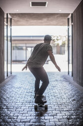 Rückansicht eines jungen männlichen Skateboarders, der in der Stadt Skateboard fährt - ISF06977