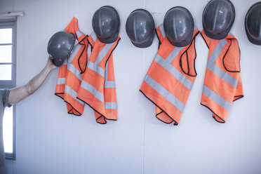 Bauarbeiter entfernen mit der Hand einen Schutzhelm von einer tragbaren Kabinenwand - ISF06978