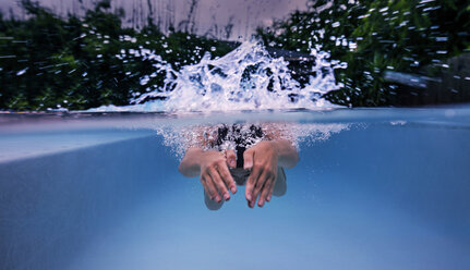 Unterwasseransicht eines schwimmenden und spritzenden Mädchens im Schwimmbad - ISF06990