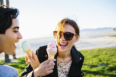 Young couple linking each others arms eating ice cream cones, Venice Beach, California, USA - ISF07001