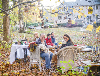 Portrait of mature couple with teenage and adult children picnicing in garden - ISF07043