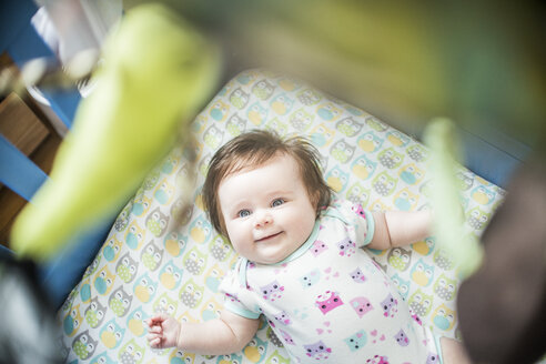 Draufsicht auf ein in einem Kinderbett liegendes lächelndes Mädchen - ISF07044