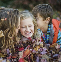 Kinder liegen auf Herbstblättern im Garten - ISF07062