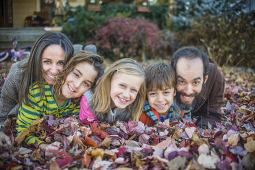Familie auf Herbstblättern im Garten liegend - ISF07064