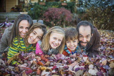 Family lying on autumn leaves in garden - ISF07064