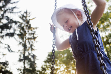 Baby girl playing on park swing, low angle view - CUF18432