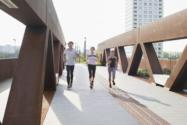 Male and female runners running on urban footbridge - CUF18486
