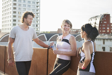 Two women and man training, chatting on footbridge - CUF18508