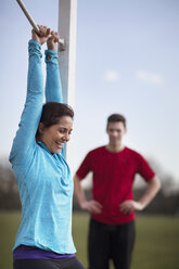 Young woman doing pull ups on playing field goal post - CUF18539