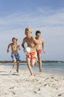 Junge läuft mit Rugby-Ball, verfolgt von Bruder und Vater am Strand, Mallorca, Spanien - CUF18542