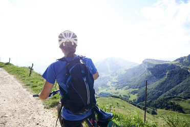 Rückansicht eines Radfahrers mit Fahrradhelm und Blick auf die Berge - CUF18678