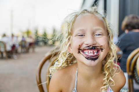Porträt eines blondhaarigen Mädchens in einem Straßencafé mit Soße im Mund, lizenzfreies Stockfoto