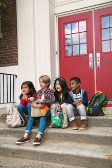 Grundschulmädchen und -jungen sitzen auf der Eingangstreppe der Grundschule - ISF07081