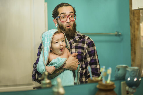Spiegelbild eines jungen Mannes und eines kleinen Sohnes, die im Badezimmer Grimassen schneiden - ISF07089