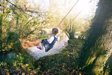 Girl playing swing by stream, Dorset - CUF18704
