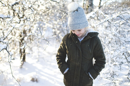 Junges Mädchen in verschneiter Landschaft, Hände in den Taschen, Blick nach unten - CUF18737