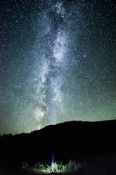 Man looking up at night sky and milky way from mountain forest, Penticton, British Columbia, Canada - ISF07096