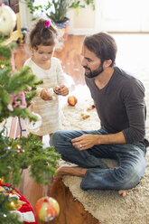 Vater und Tochter schmücken den Weihnachtsbaum - ISF07112