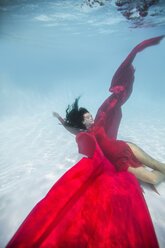 Woman wearing red dress,draped in red fabric, floating underwater - ISF07131