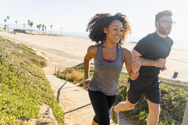 Couple running along pathway by beach - ISF07147