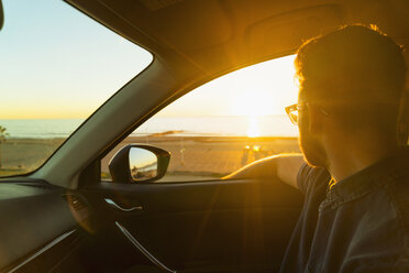 Junger Mann schaut bei Sonnenuntergang aus dem Autofenster - ISF07150