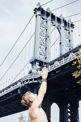 Mann meditiert mit erhobenen Händen vor der Manhattan Bridge, New York, USA - ISF07171