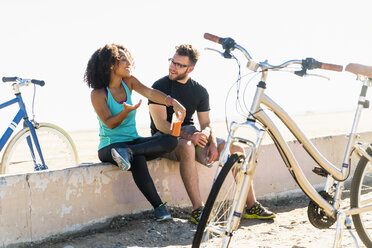 Paar sitzt auf einer Mauer und macht eine Pause, neben ihnen Fahrräder - ISF07177