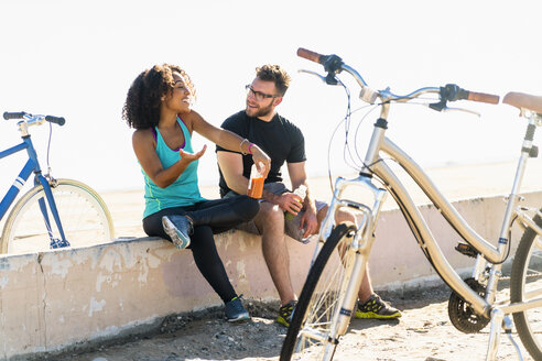 Couple sitting on wall, taking a break, bicycles beside them - ISF07177