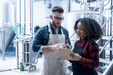 Colleagues in brewery looking at clipboard smiling - ISF07202