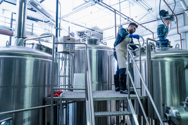 Junger Mann in einer Brauerei mit Schürze testet Bier im Tank - ISF07206