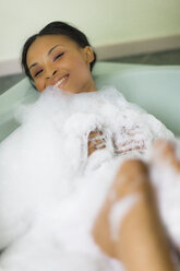 Porträt einer jungen Frau, die sich im Schaumbad entspannt, bedeckt mit Blasen - ISF07221