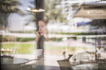 Frau, die hinter ein reflektierendes Café-Fenster blickt, Dubai, Vereinigte Arabische Emirate - CUF18937