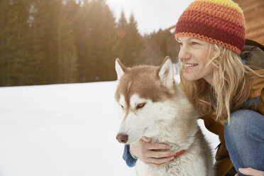 Frau kniend mit Husky in verschneiter Landschaft, Elmau, Bayern, Deutschland - CUF18958