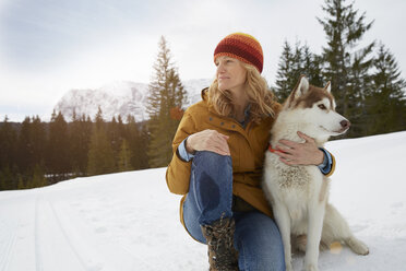 Woman sitting with husky in snow covered landscape, Elmau, Bavaria, Germany - CUF18959